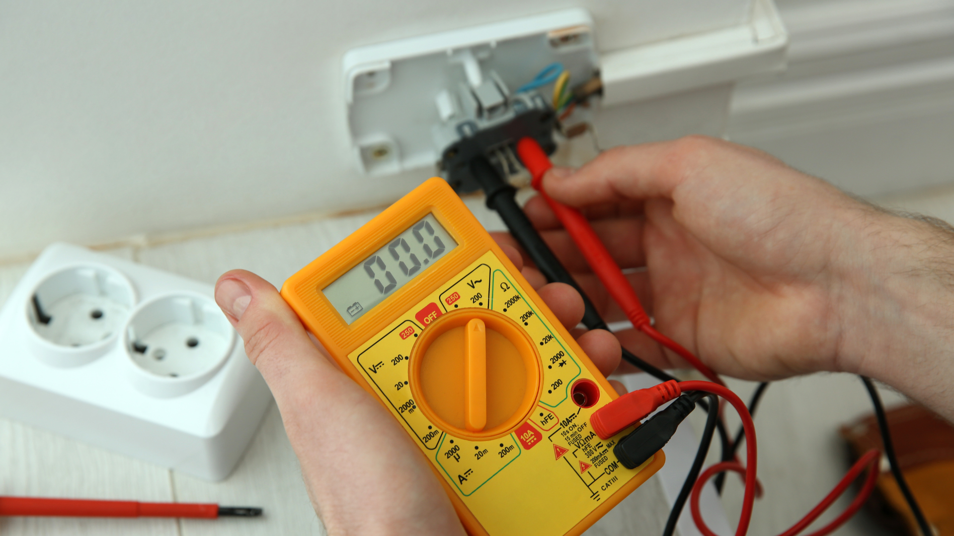 Electrician testing a socket with a multimeter during a home electrical inspection